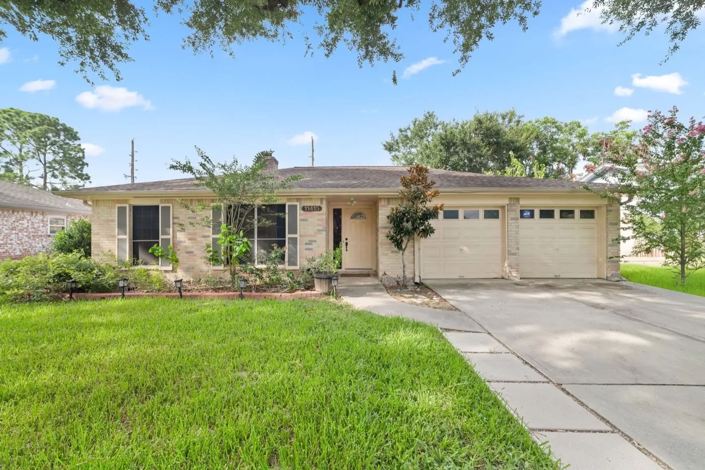 Tan brick house with a two-car garage, bought by Tara Pays Cash