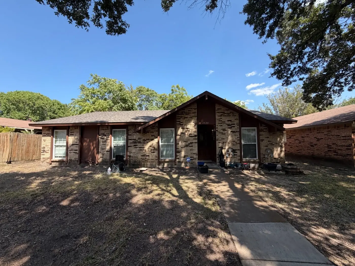 Brick ranch house with a shaded yard, bought by Tara Pays Cash
