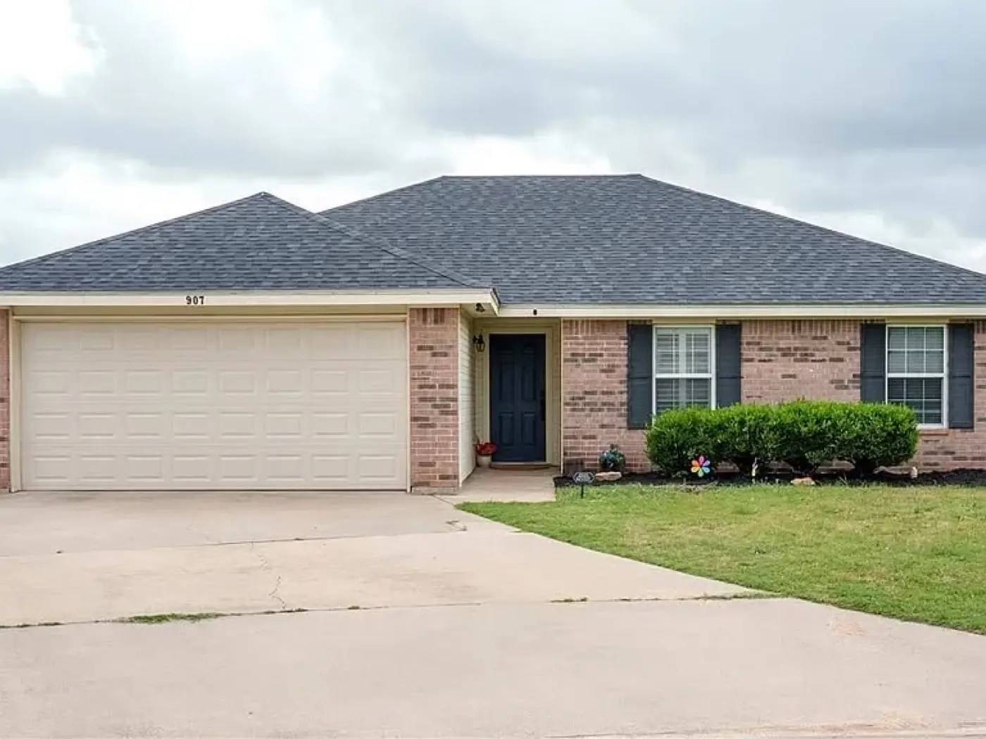 Brick house with dark shutters and a wide driveway, bought by Tara Pays Cash