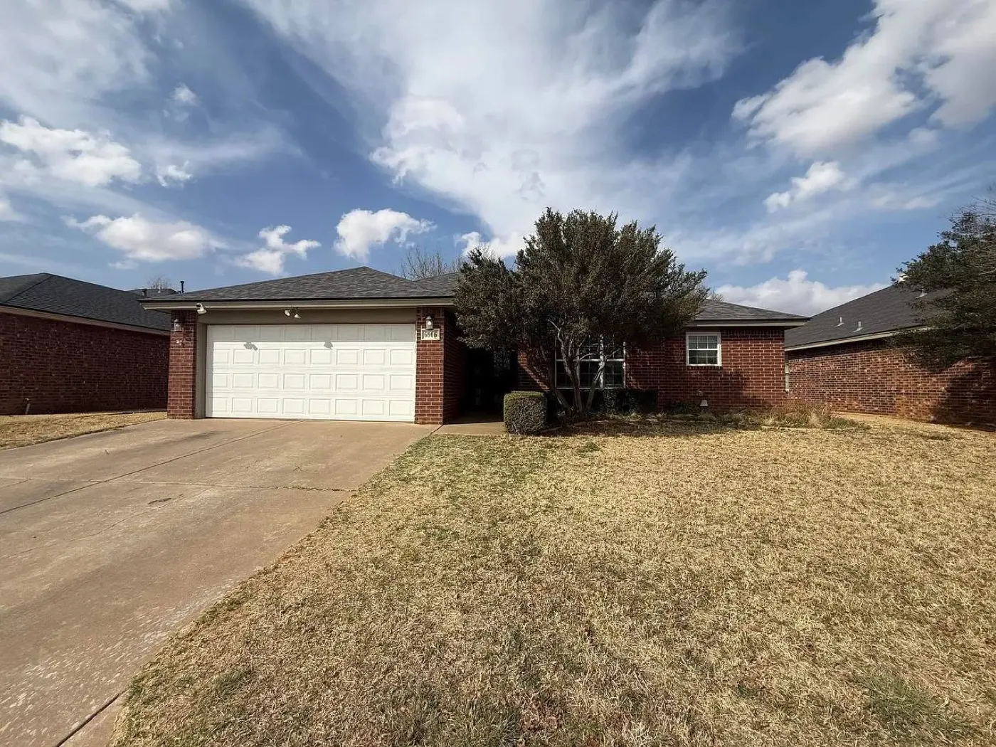Red brick house with a two-car garage, bought by Tara Pays Cash